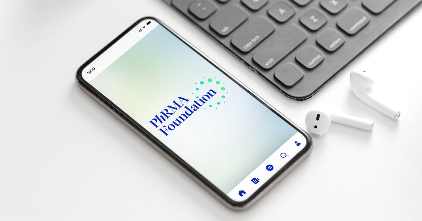 A mockup of a smart phone with an app start-up screen with the PhRMA Foundation logo centered in the screen